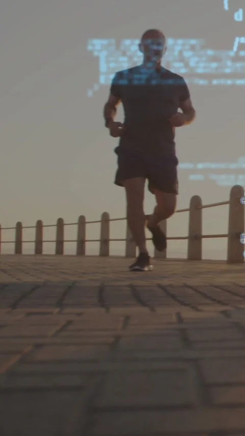 Vertical video: Senior runner closing to cam on coast, making blue code overlay Stock Footage 331215752