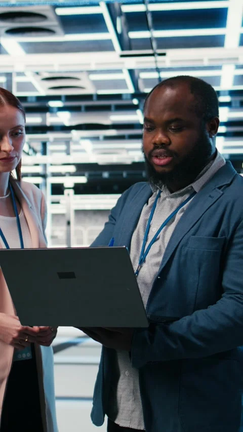 Vertical video Server farm manager teaching intern to use laptop and optimize Stock Footage 330085697