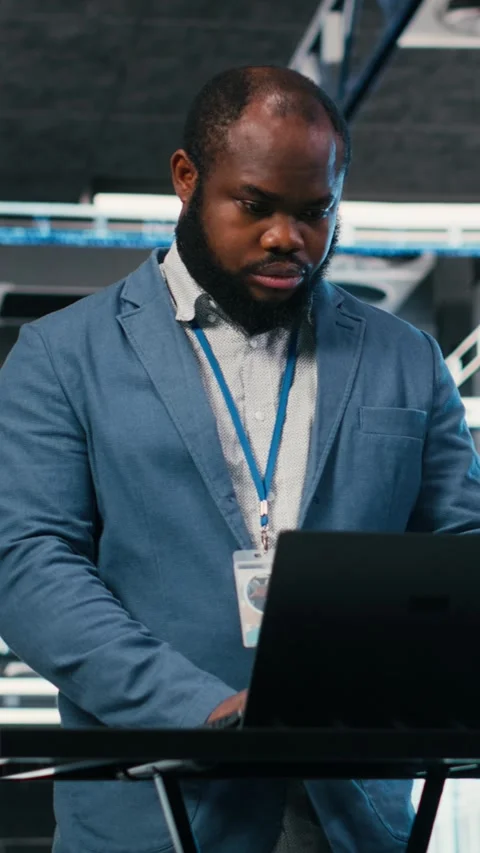 Vertical video Server farm programmer at workplace desk using laptop to optimize Video stock 330086160