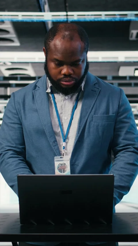 Vertical video Server farm programmer at workplace desk using laptop to optimize Video stock 330139416