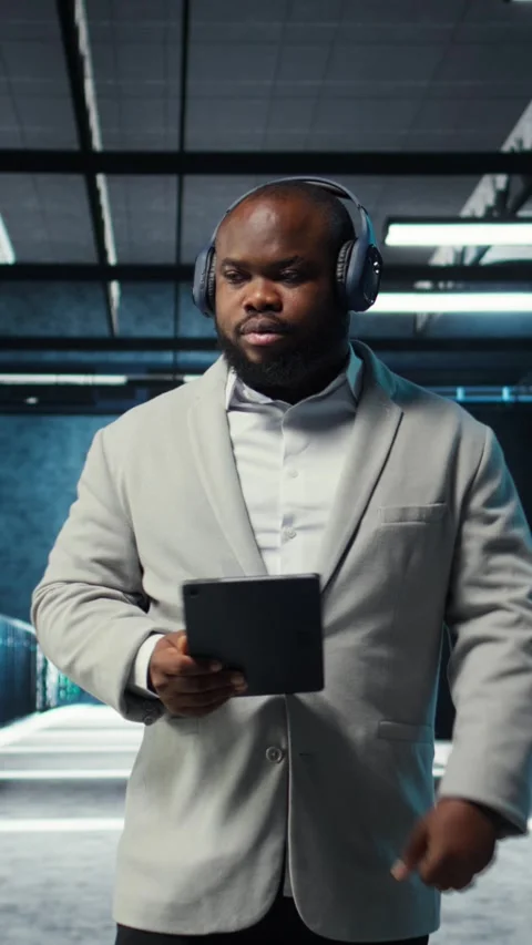 Vertical video Server room programmer wearing headphones troubleshooting errors Stock-Footage 311601069