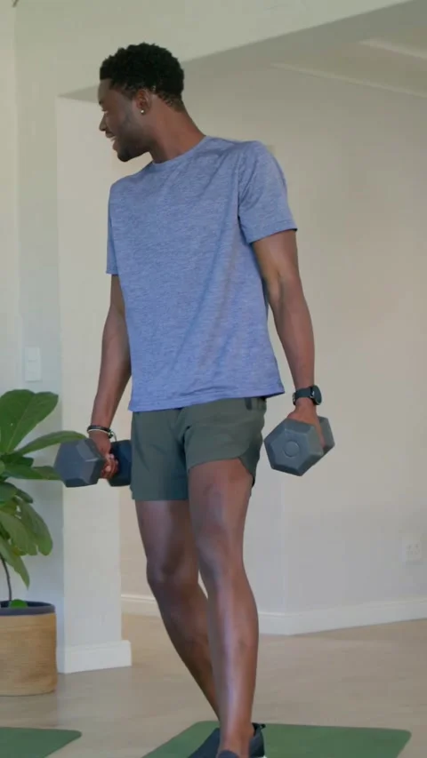 Vertical video: Shifting, man doing reverse lunges on home mat in blue tee with Stock-Footage 348203292