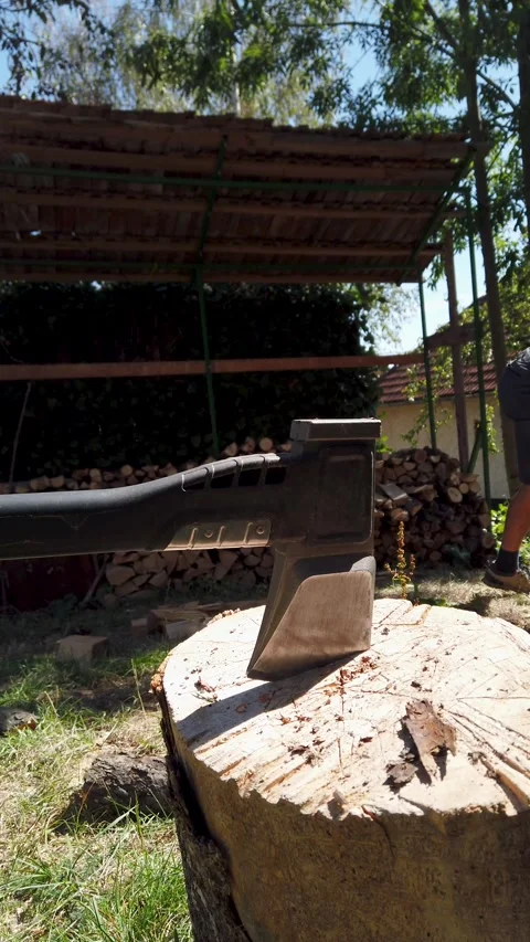 Vertical video of shirtless man stacking firewood log pile chopped with axe Stock Footage 345587809