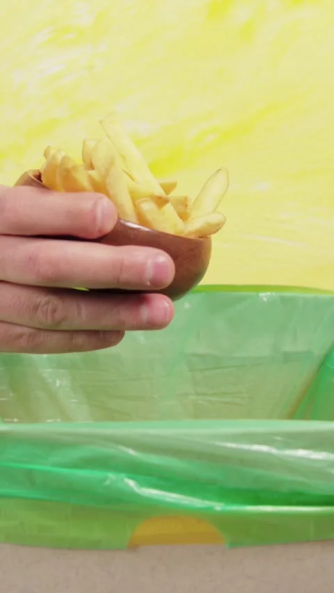 Vertical video shot showing a hand tossing a slice of pizza into a garbage bin Stock Footage 345212344