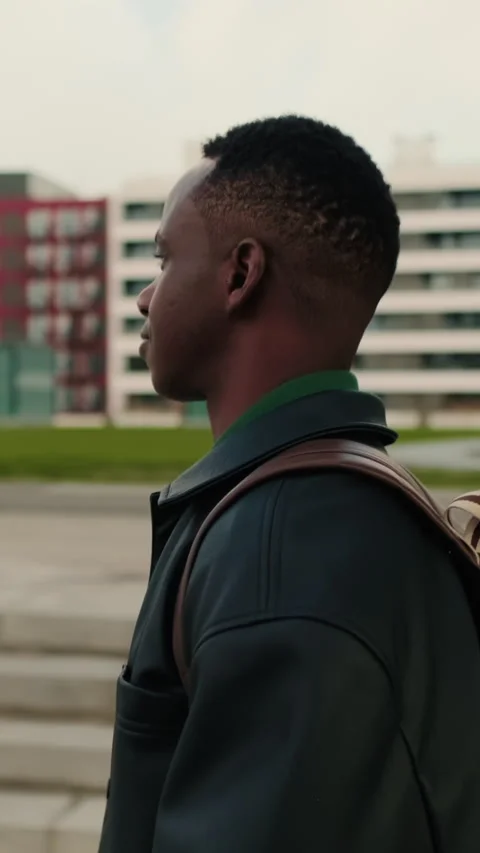 Vertical video, Side view Young Man Walking Through City in urban setting Stock Footage 320007084
