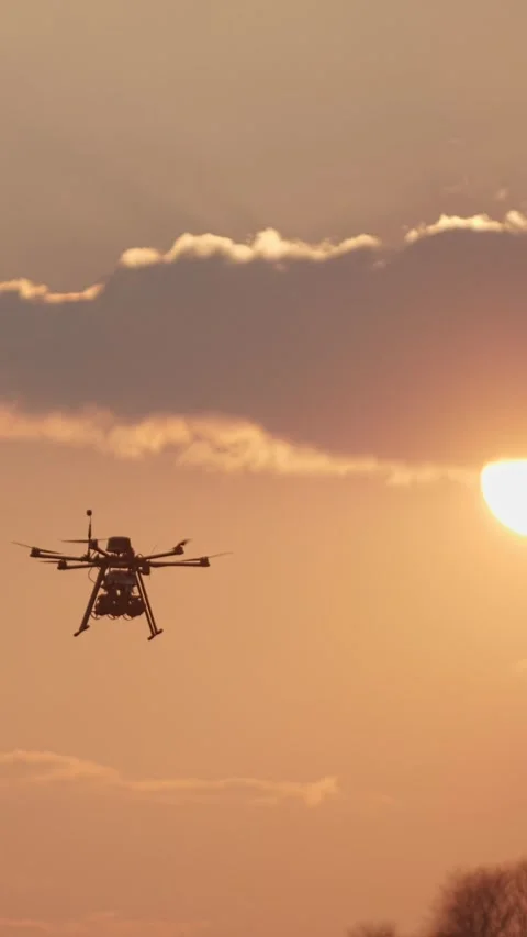 Vertical video. Silhouette of a hexacopter drone flying at sunset Video stock 335543108