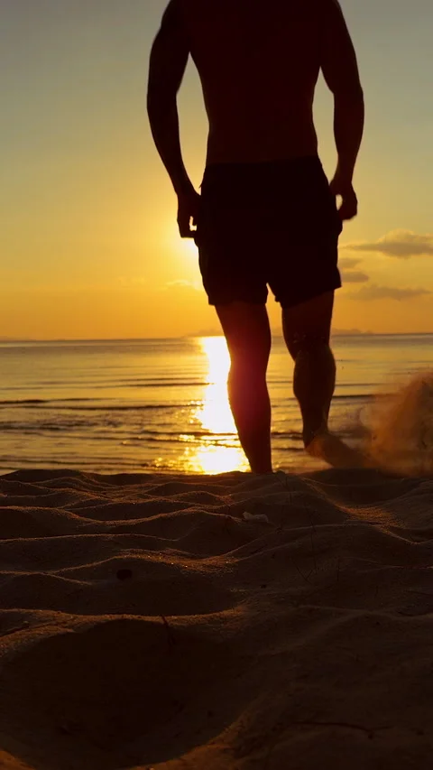 Vertical video. Silhouette Of Man Running Toward Ocean Across Sandy Beach During Stock Footage 331875752