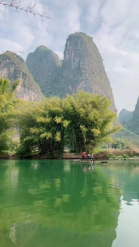 Vertical Video of a Single Bamboo Raft Drifting Past Guilin Karst Mountains Video stock 328439846