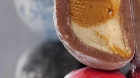 Vertical video. Six cut mochi cakes spin on a mirror surface. Presentation of Video stock 254488652
