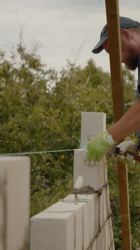 Vertical video Skilled worker builds a concrete brick wall for new home Video stock 327601878