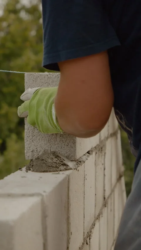 Vertical video Skilled worker builds a concrete wall for new home construction Video stock 327602099