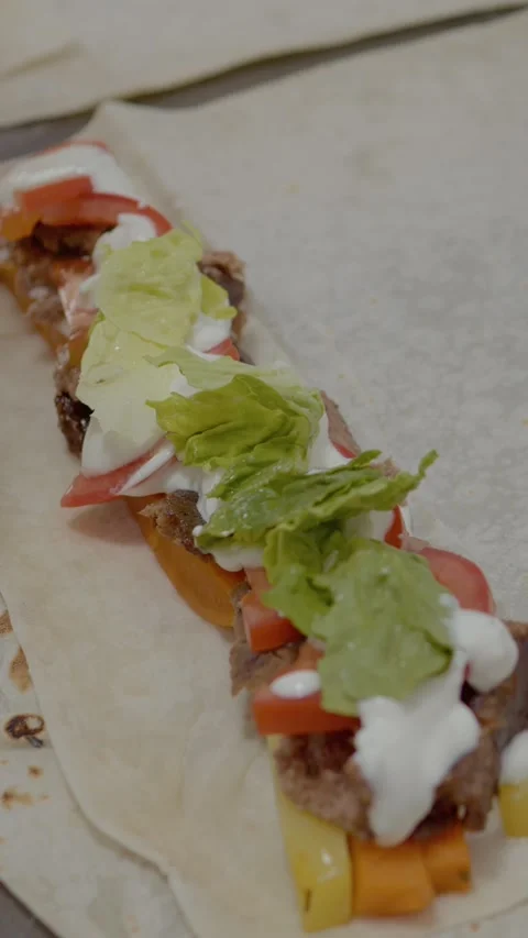 Vertical video Skillful hand preparation of a tasty kebab with fresh toppings Stock Footage 329626406