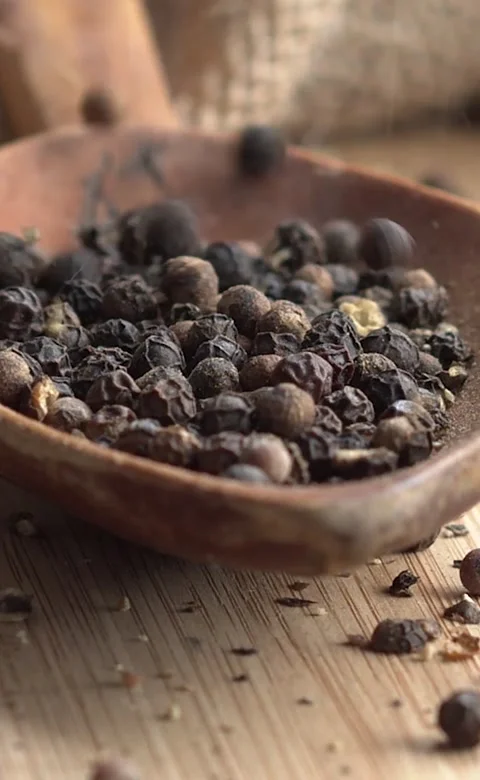 Vertical video. Slow motion of black peppercorns giving way on a wooden board Stock Footage 224496868