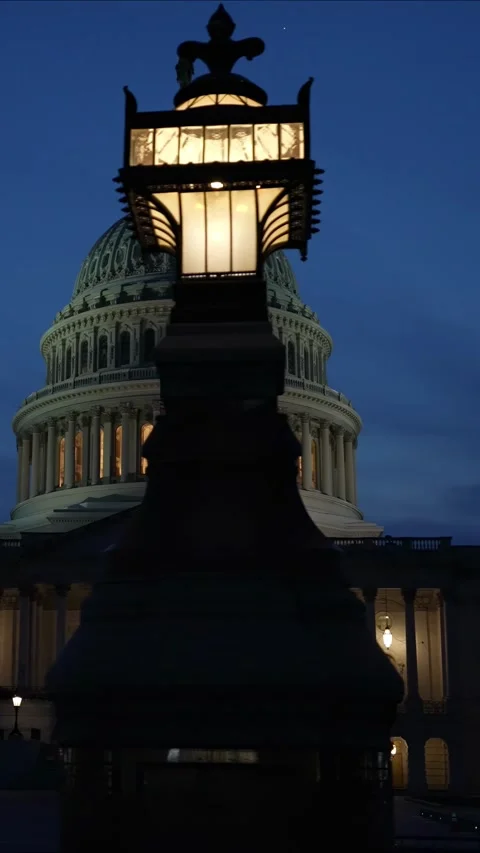 Vertical video slow motion to left showing the US Capitol with lights and flags Stock Footage 314658442