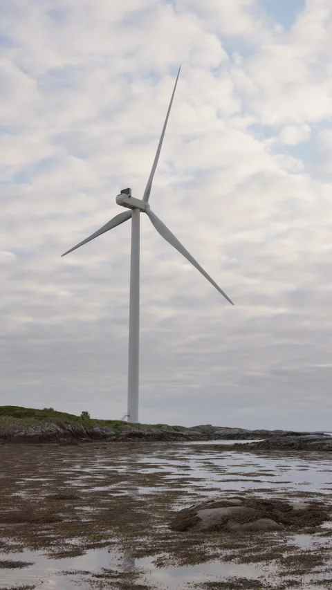 Vertical video of small Coastal Wind Turbine Standing on Rocky Shore. Video stock 337049337