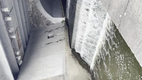 Vertical video small grey concrete dam in city with waterfall moving into river Stock Footage 294263023