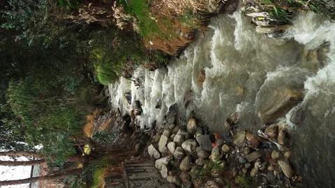 Vertical video of a small mighty river that crosses between two houses with Stock Footage 164566368