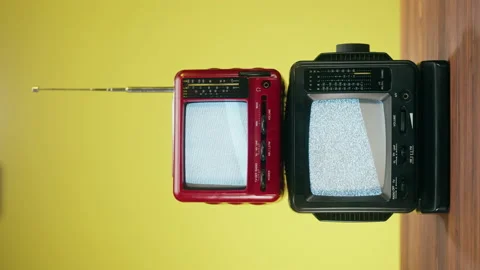 Vertical video of small old televisions with grey interference screen on yellow Stock Footage 169734554