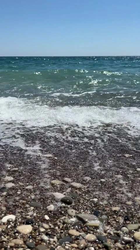 Vertical video of a small sea wave rolling onto the shore, close-up Stock Footage 308929428