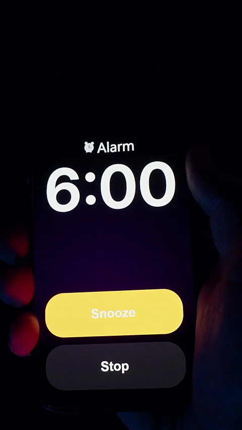 Vertical video. Smartphone Screen Displays Alarm Set for 6 AM Held in Hand Under Stock Footage 319886521
