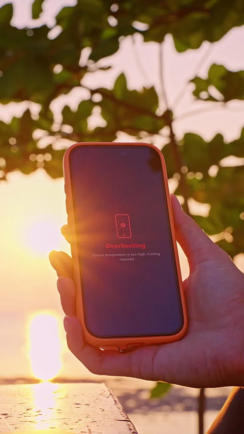 Vertical video. Smartphone Screen Showing Overheating Warning Message in Hand at Stock Footage 332306463