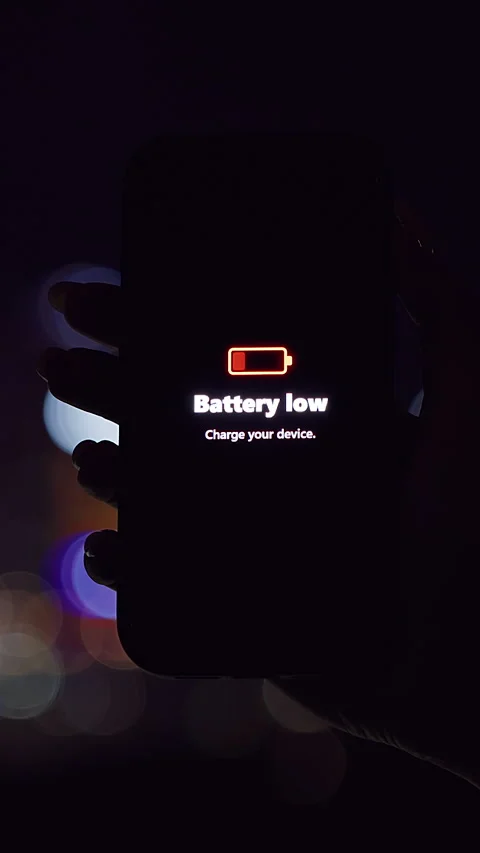 Vertical video. Smartphone Showing Battery Low Warning Held Against Colorful Nig Video stock 323466784