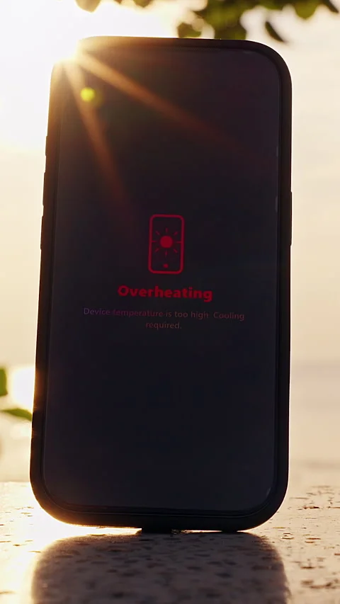 Vertical video. Smartphone Showing Overheating Warning Standing On Outdoor Table Stock Footage 330884055