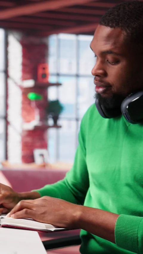 Vertical Video Smiling black man taking notes while watching a tutorial Stock Footage 307643987