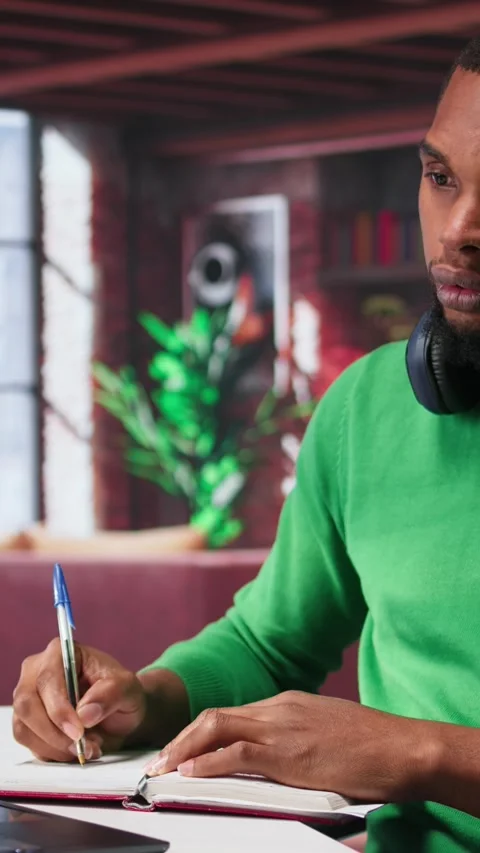 Vertical Video Smiling black man taking notes while watching a tutorial 動画素材 308707083