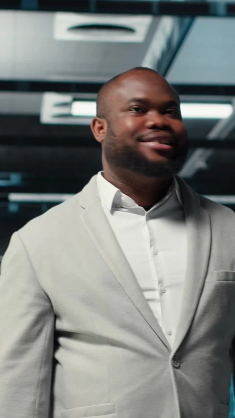 Vertical video Smiling engineer walking in data center, checking hardware for Stock Footage 311340675