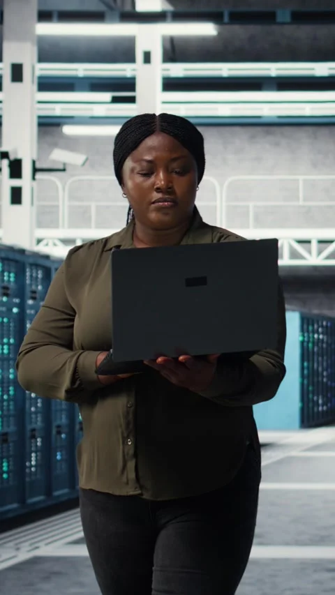 Vertical video Smiling engineer walking in data center with laptop, checking Stock Footage 316862762