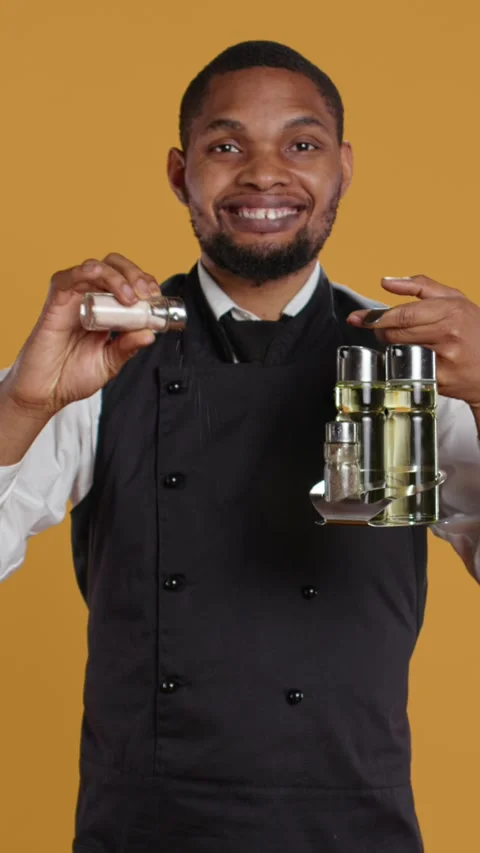 Vertical Video Smiling friendly waiter pouring down salt from the salt shaker on Stock Footage 279688616