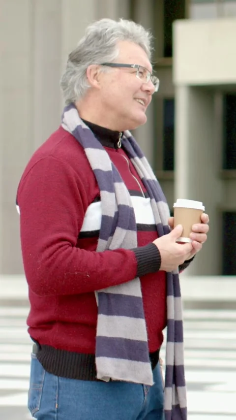 Vertical video: Smiling man in red sweater, scarf greeting arriving friend at Stock Footage 348491555