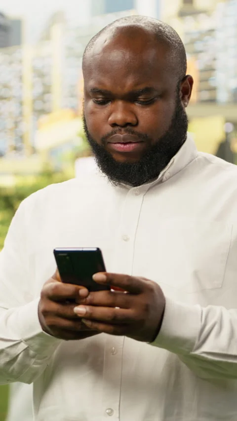 Vertical Video Smiling man scrolling mobile phone and looking toward camera Stock Footage 344378285