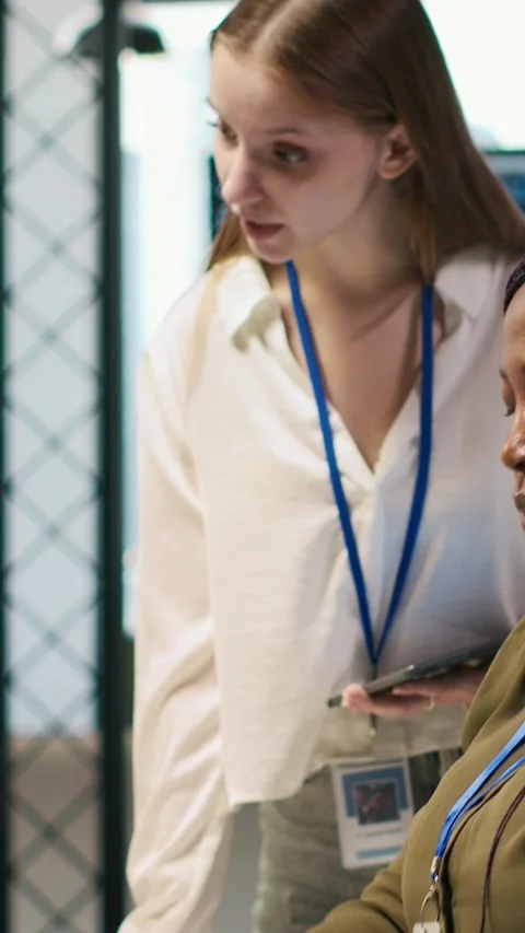 Vertical video Smiling startup manager teaching junior dev how to use machine Stock Footage 312708663