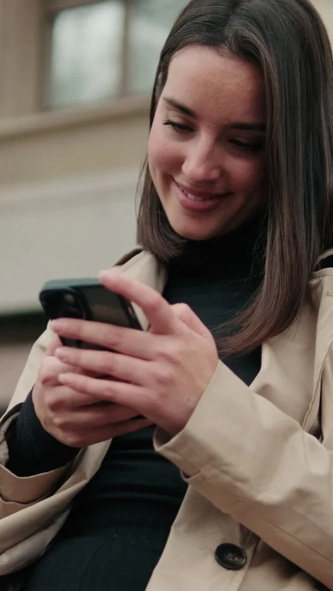 Vertical video, Smiling Woman Using Smartphone on City Bench Stock Footage 304815706