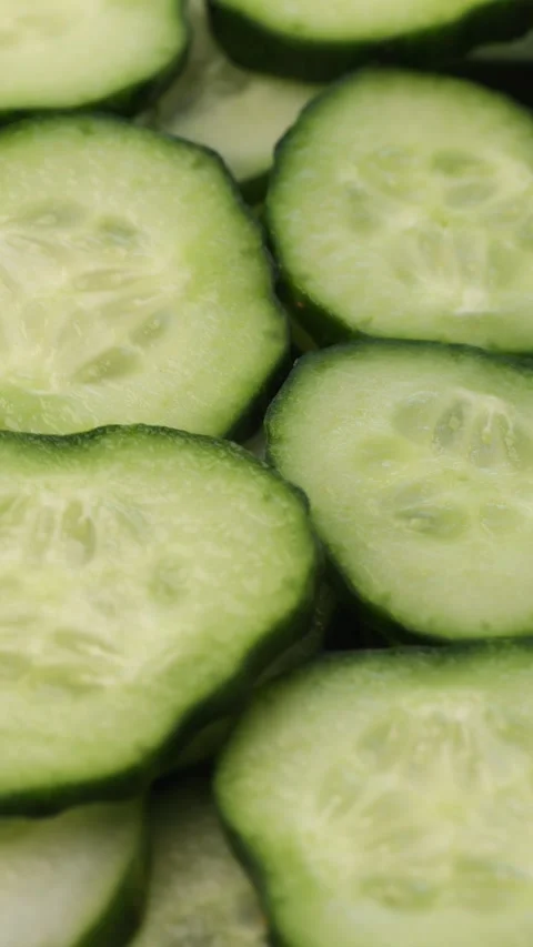 Vertical video. Smooth rotation of fresh cucumber slices in close-up. Green Stock Footage 304682939
