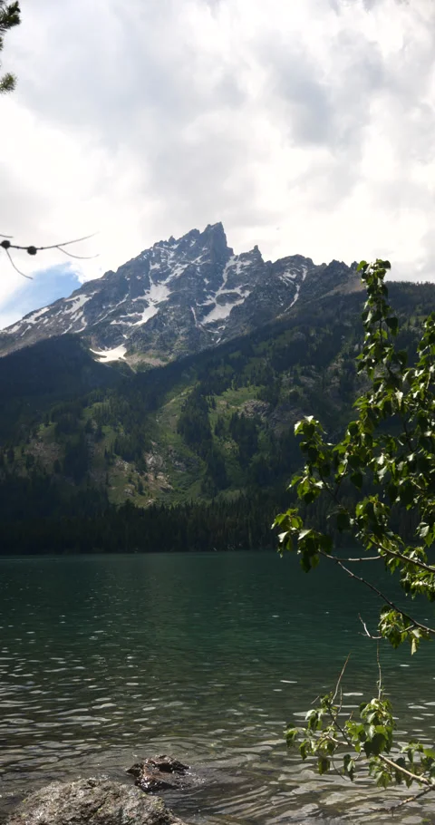 Vertical video of snow-capped mountain peaks beside a peaceful alpine lake Stock Footage 341433341