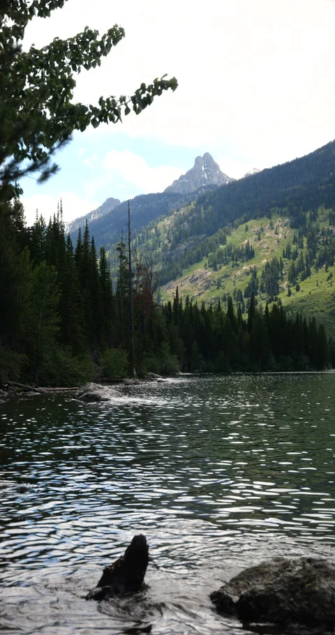 Vertical video of snow-capped mountain peaks beside a peaceful alpine lake Stock Footage 341433532