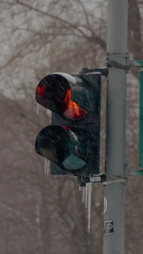Vertical video Snow falls softly over city streets with a traffic light glowing Stock Footage 317978226