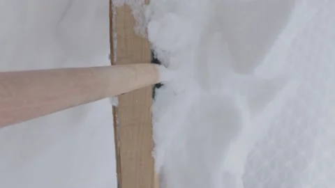 Vertical video. Snow removal in the backyard with a wooden shovel. Video stock 220132853