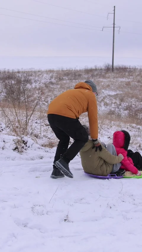 Vertical video. A snow slide where a family is having fun on plastic sleds Stock-Footage 301554475