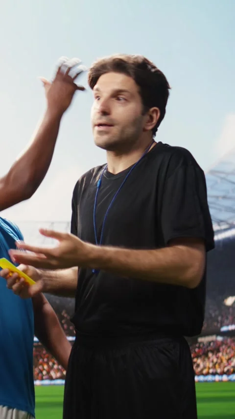 Vertical Video Soccer referee stopping heated argument with yellow card raised Stock Footage 338046994