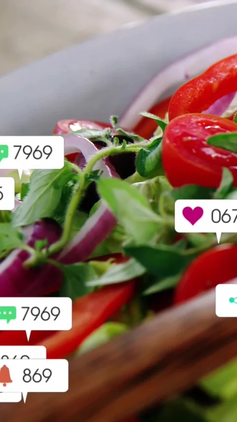 Vertical video: Social post uploading causing icons growing over salad on table Stock Footage 331738897