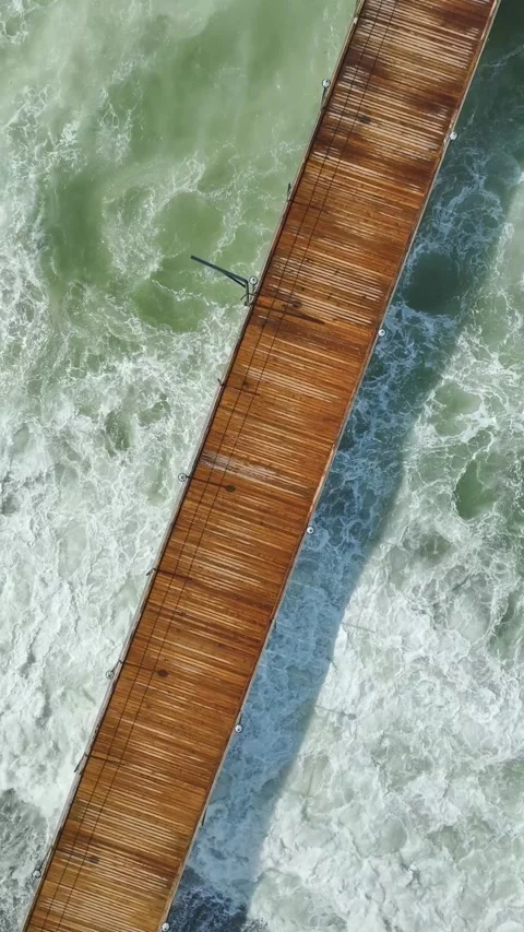 Vertical Video of Soft Rolling Waves Under Coastal Pier With Sun Umbrellas and Stock Footage 342305974