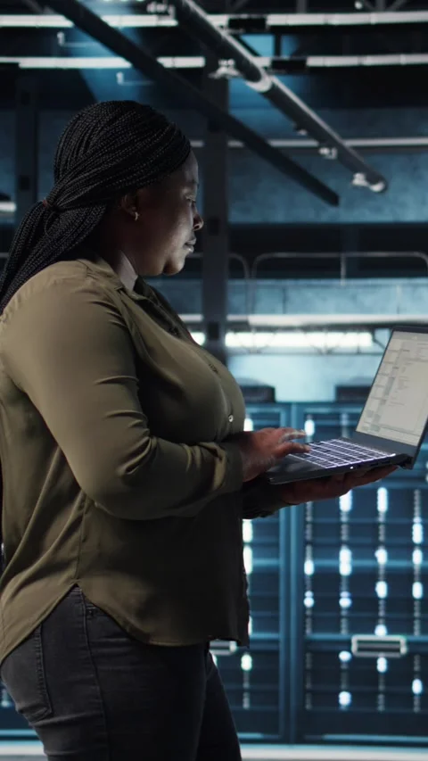 Vertical video Software developer in data center using laptop to deploy new Stock Footage 317056116