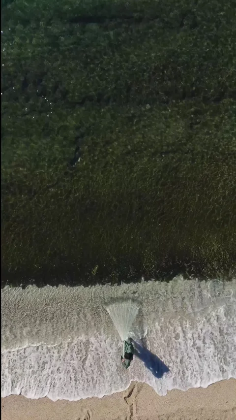 Vertical Video of a Solo Fisherman Casting a Large Net Into the Sea Surrounded Stock Footage 300344619