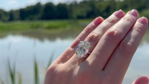 Vertical video of sparkling engagement ring with oval diamond outdoors Stock Footage 316901568