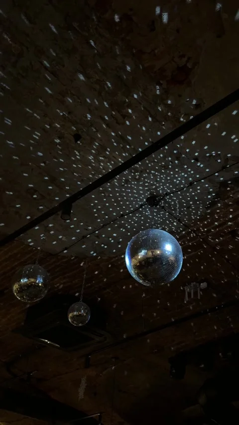 Vertical video of spinning disco ball with silver mirror panels reflecting light Stock Footage 322052578