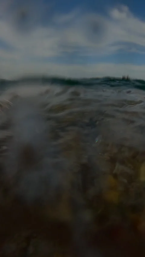 Vertical video, Split level, Underwater view of sea waves roll on pebbles shore 스톡 동영상 332920457